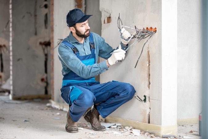 Electrician mounting wiring indoors