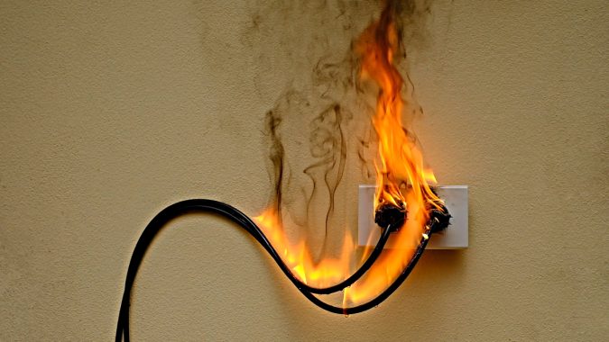 On fire electric wire plug Receptacle on the concrete wall backg